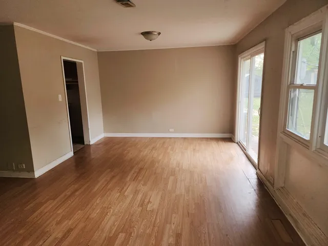 an empty room with wooden floor and windows