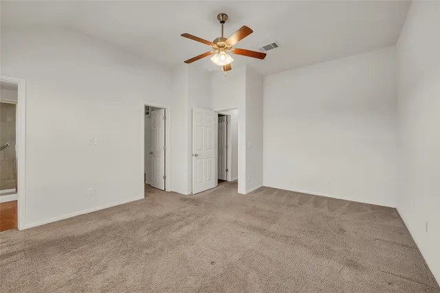 an empty room with a chandelier fan and windows