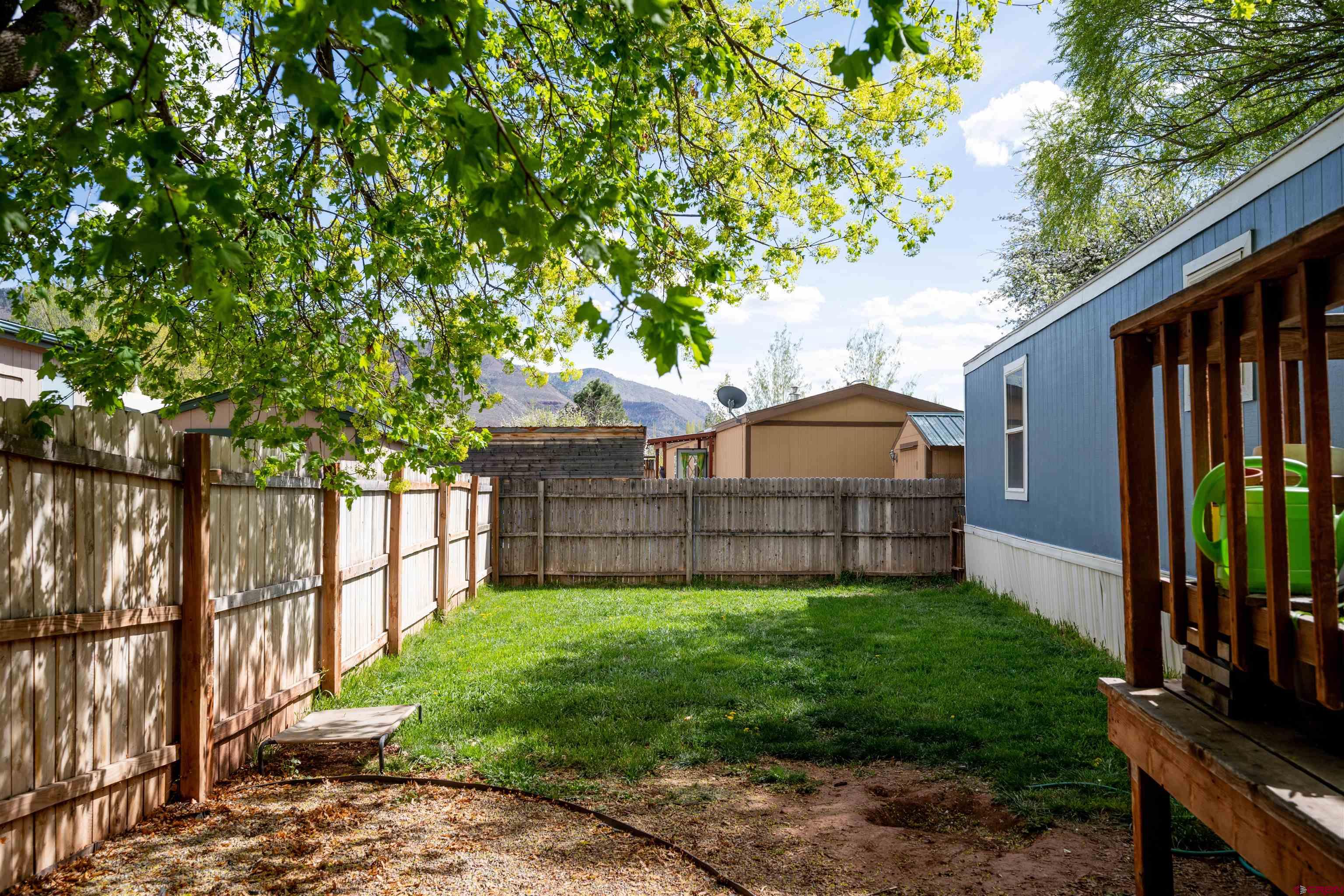 2 Mulberry Way Durango, CO 81301 - Photo 37 of 40 a view of a small yard in front of a house with a large tree and wooden fence