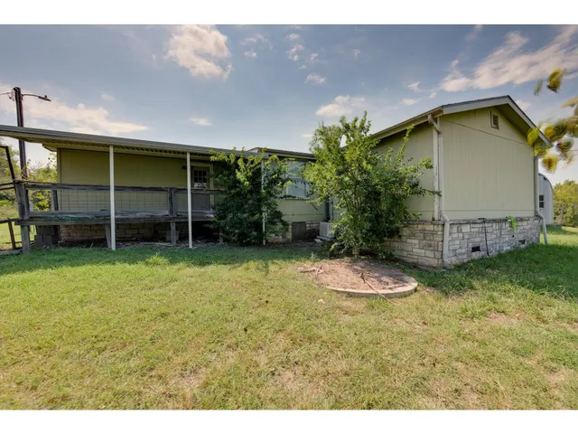 a backyard of a house with wooden fence and a bench