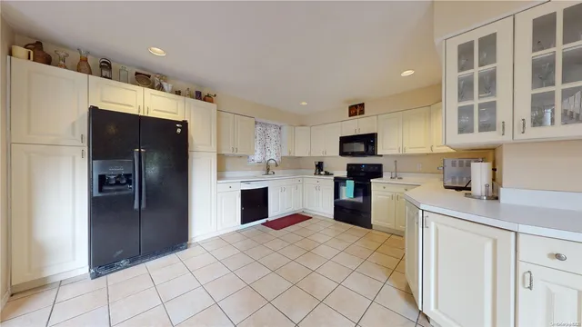 a kitchen with stainless steel appliances kitchen island granite countertop a refrigerator oven a sink dishwasher and white cabinets with wooden floor