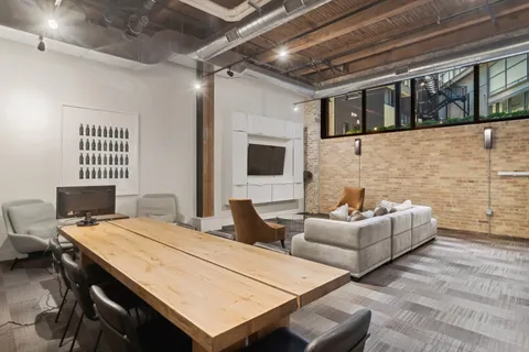 a living room with couches a fireplace and a dining table with wooden floor
