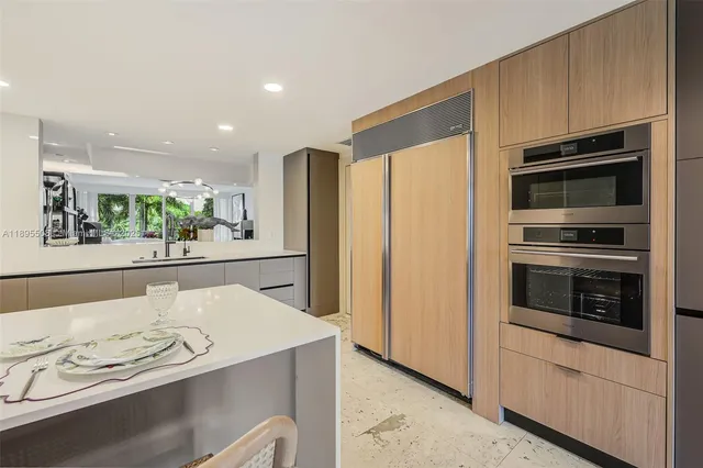 a kitchen with stainless steel appliances kitchen island granite countertop a refrigerator oven a stove with white cabinets and wooden floor