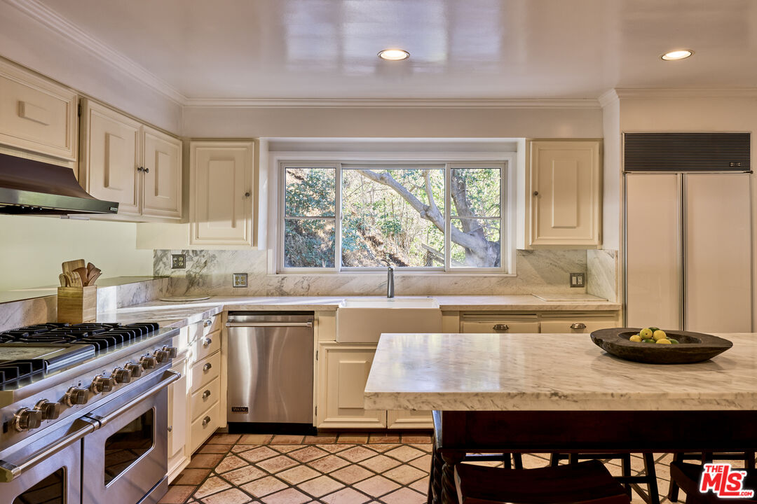 3268 Serra Road Malibu, CA 90265 - Photo 13 of 24 a kitchen with a sink stove and cabinets