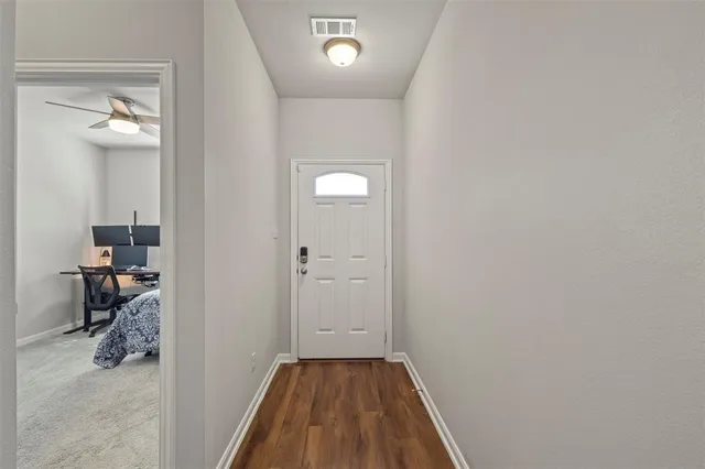 a view of a hallway with wooden floor and a bathroom