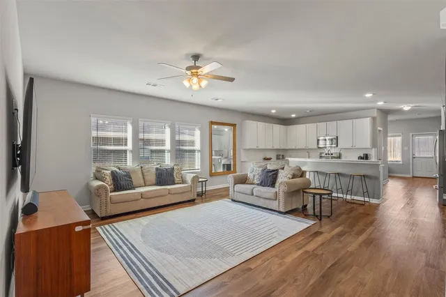 a living room with furniture two window and wooden floor