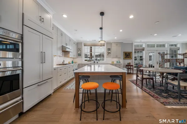 a dining hall with stainless steel appliances granite countertop a table and chairs