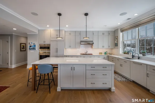 a kitchen with stainless steel appliances granite countertop a table chairs stove and microwave