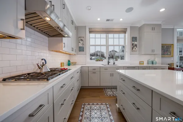 a kitchen with stainless steel appliances granite countertop a stove refrigerator a dining table and chairs with wooden floor