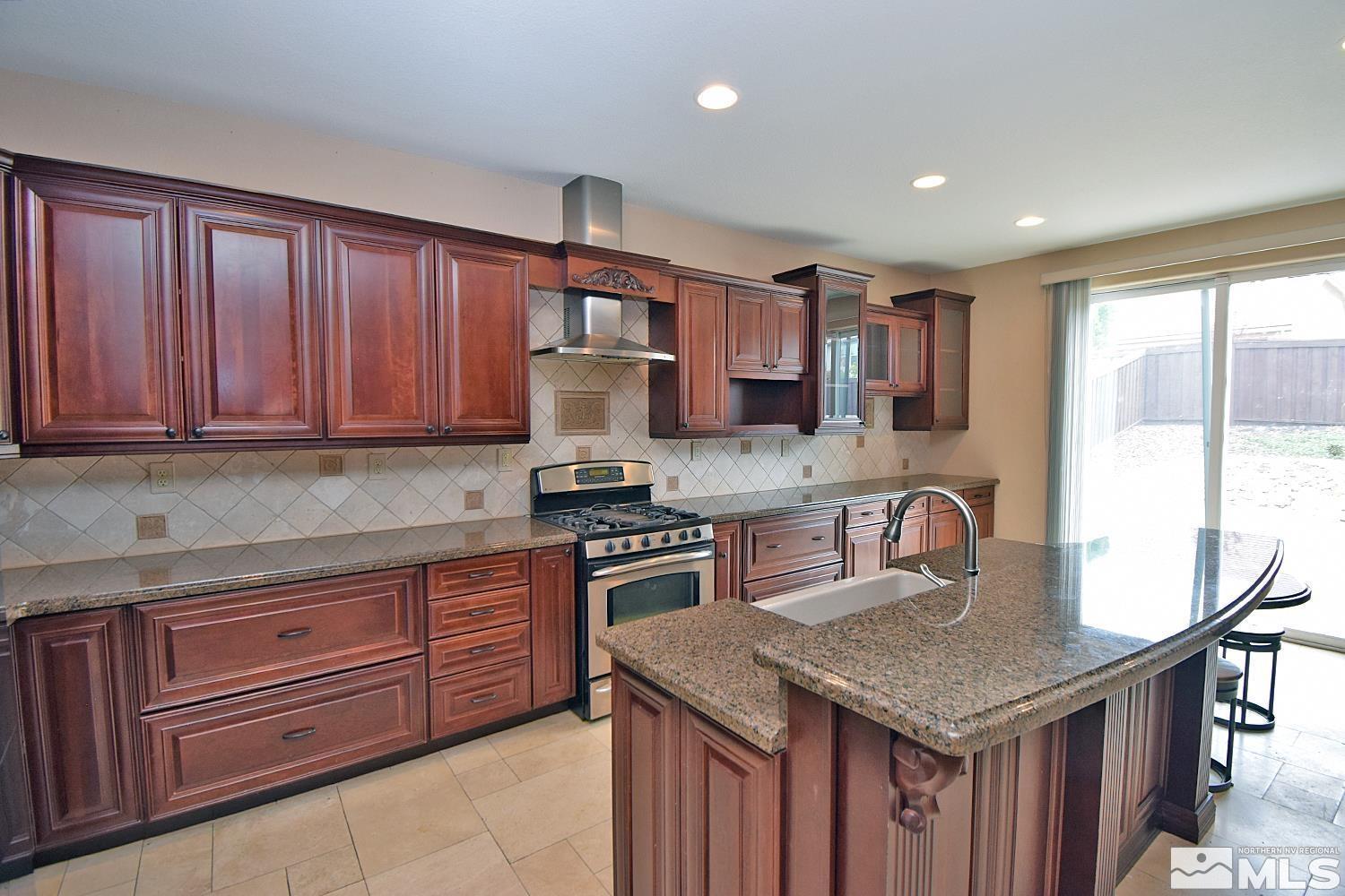 410 Teramo Court Reno, NV 89521 - Photo 7 of 32 a kitchen with granite countertop stainless steel appliances a stove sink and cabinets