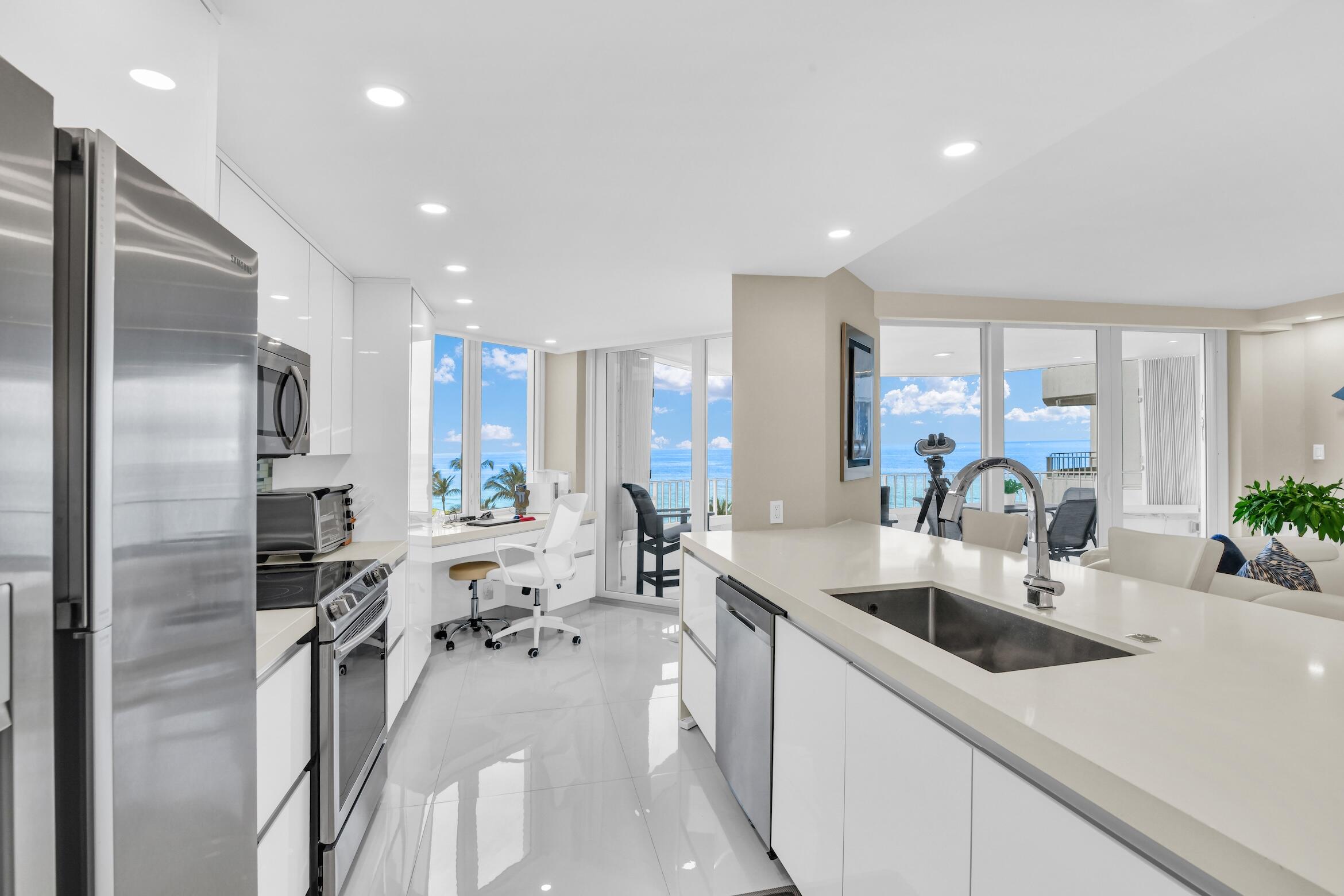 550 South Ocean Boulevard, Unit 605 Boca Raton, FL 33432 - Photo 9 of 51 a kitchen with stainless steel appliances a sink a stove a refrigerator cabinets and a dining table with wooden floor