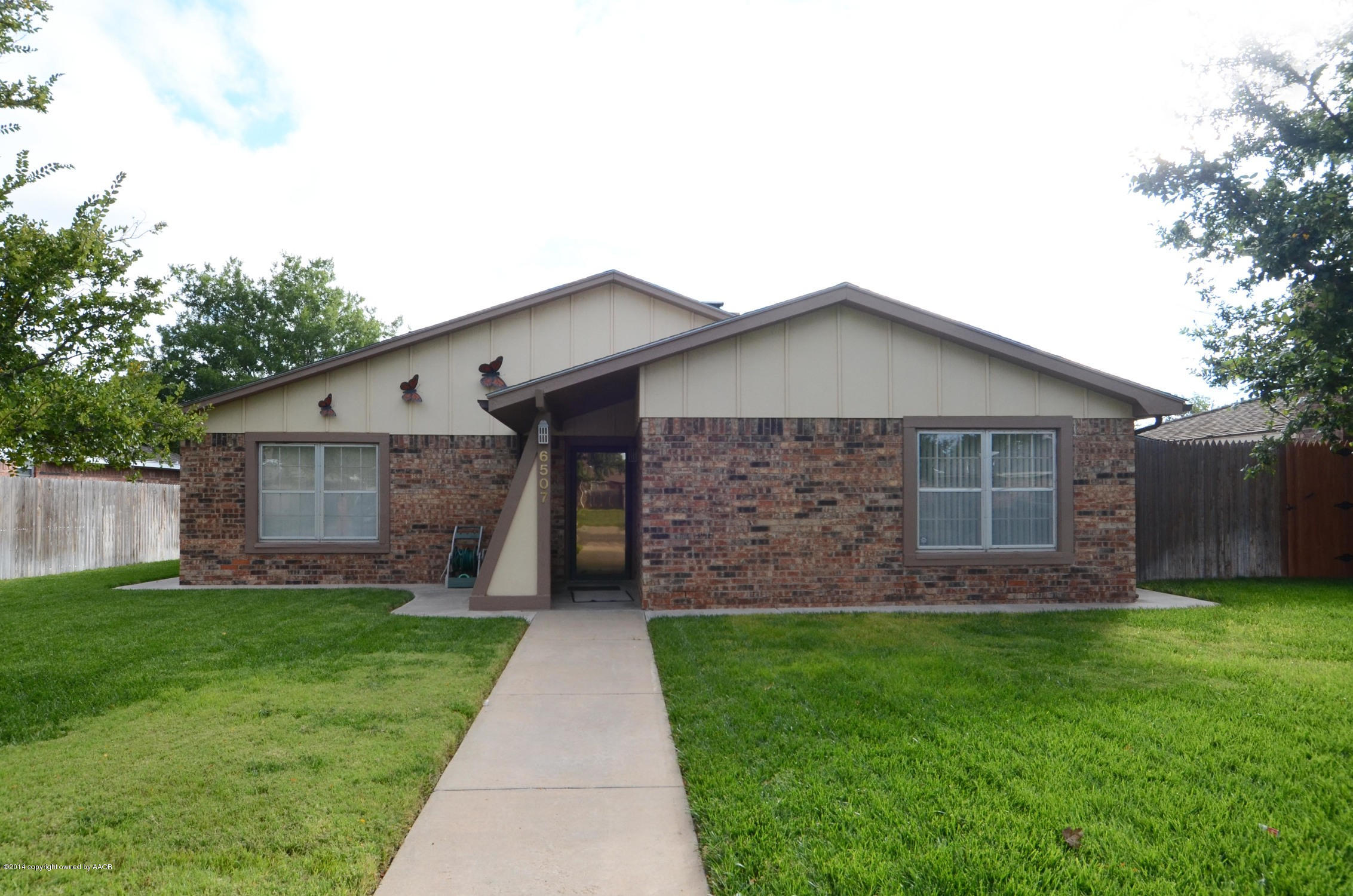 a front view of house with a garden and trees