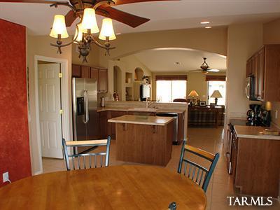 62195 East Northwood Road Tucson, AZ 85739 - Photo 15 of 25 a kitchen with stainless steel appliances granite countertop a refrigerator a sink dishwasher a stove and a dining table with wooden floor