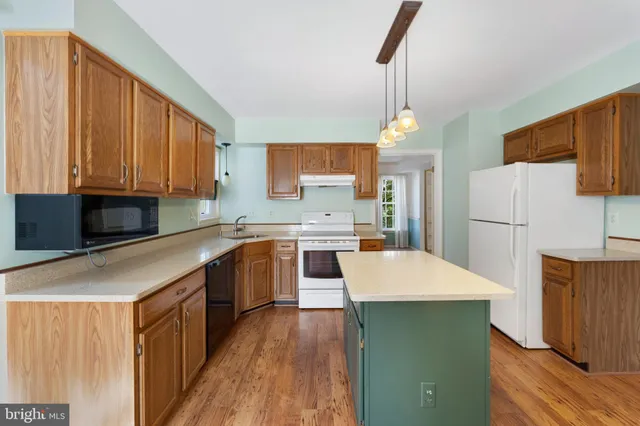 a kitchen with a refrigerator a microwave oven a sink and dishwasher with wooden floor