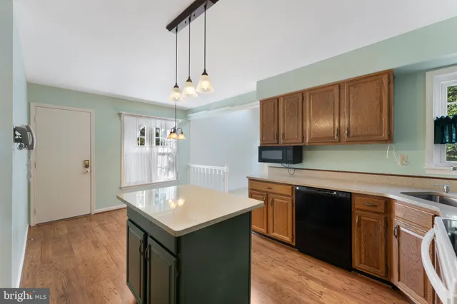 a kitchen with kitchen island granite countertop a sink cabinets and wooden floor