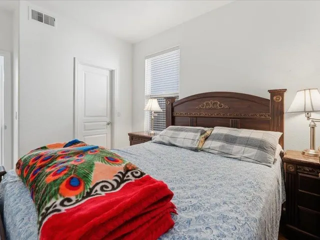 a bedroom with a bed and a lamp on dresser