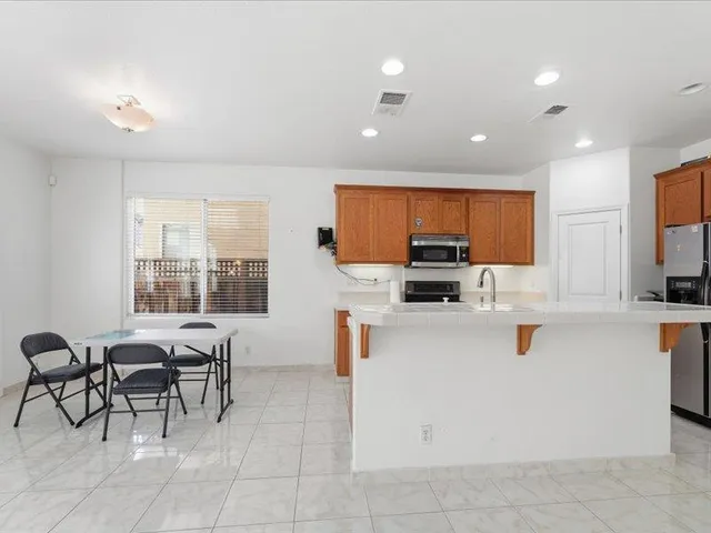 a kitchen with stainless steel appliances a stove a sink a oven a dining table and chairs