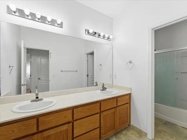 a bathroom with a double vanity sink a mirror and a bathtub