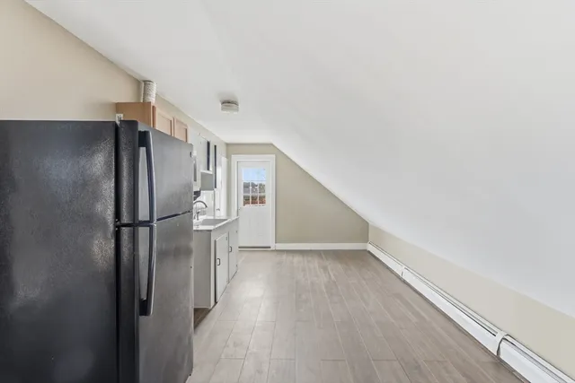 a view of a kitchen with a refrigerator and wooden floor