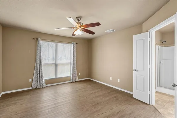 an empty room with wooden floor closet and windows