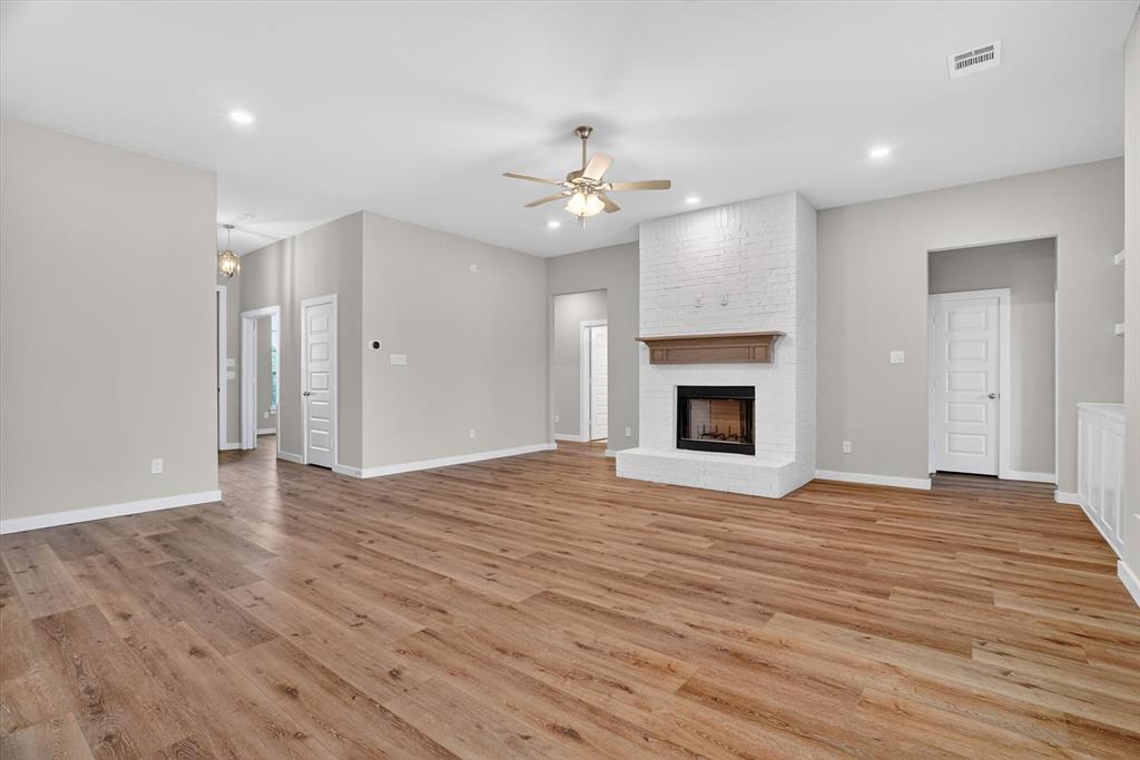 504 Clifton Court Springtown, TX 76082 - Photo 8 of 36 Spacious interior room featuring wood-finish flooring, a white brick fireplace with a wood mantel, recessed lighting, and a ceiling fan