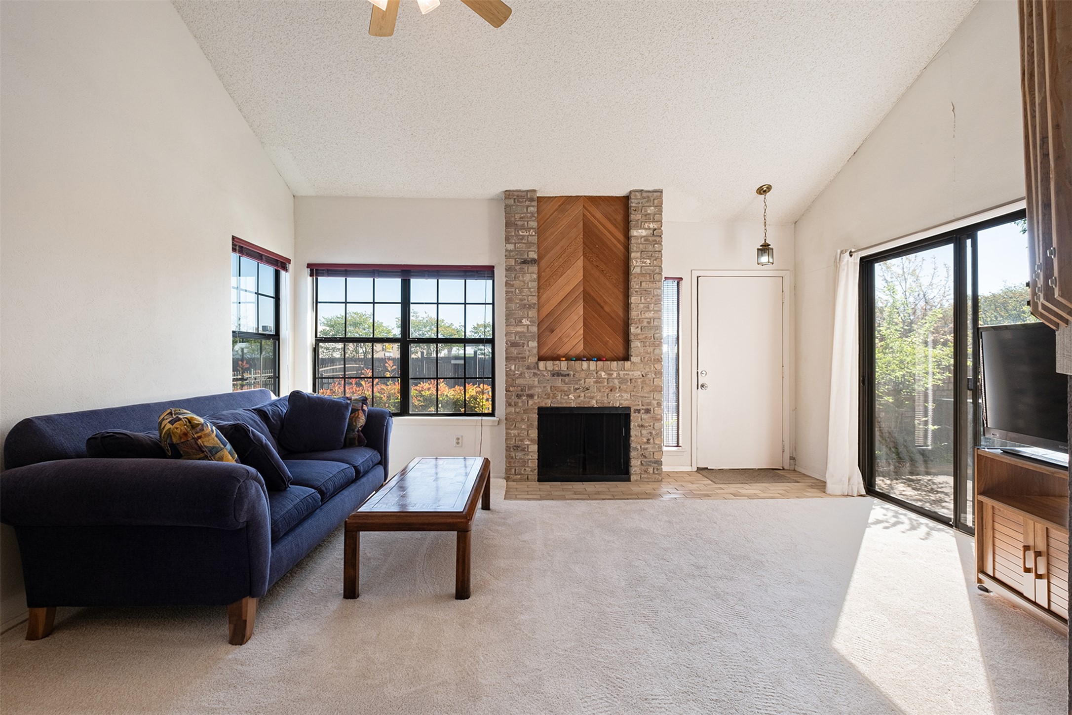 1748 Ohlen Road, Unit 16 Austin, TX 78757 - Photo 9 of 38 Living area with light carpet, ceiling fan, a high textured ceiling, and a fireplace