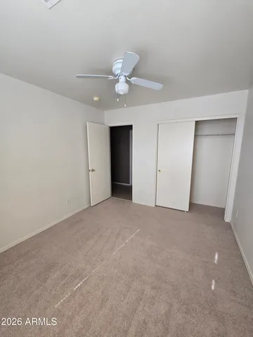 a view of an empty room with a ceiling fan and window