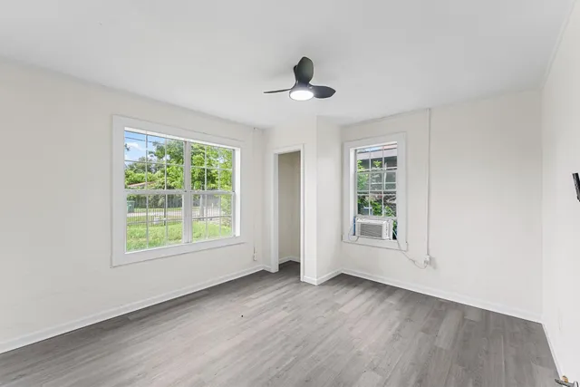 a view of an empty room with wooden floor and a window