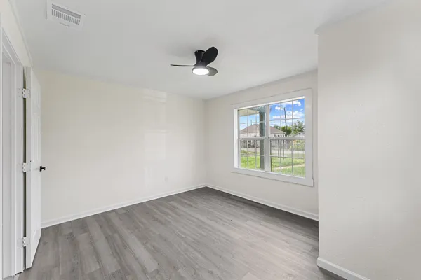 an empty room with wooden floor and windows