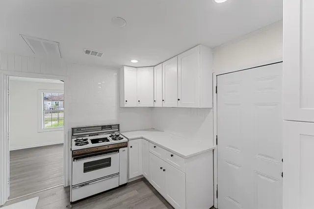 a kitchen with cabinets stainless steel appliances and wooden floor
