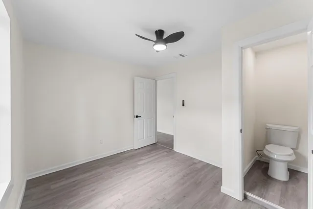 a view of a hallway with wooden floor and a toilet