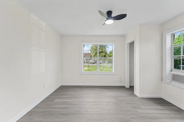 an empty room with ceiling fan and windows