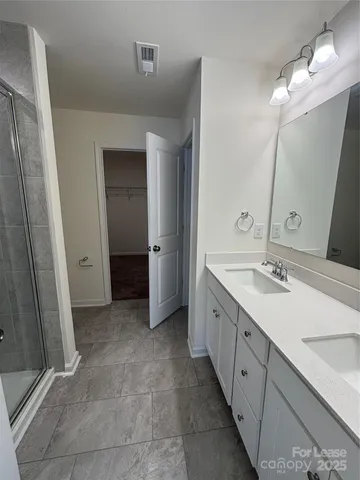 a spacious bathroom with a double vanity sink a mirror and a shower