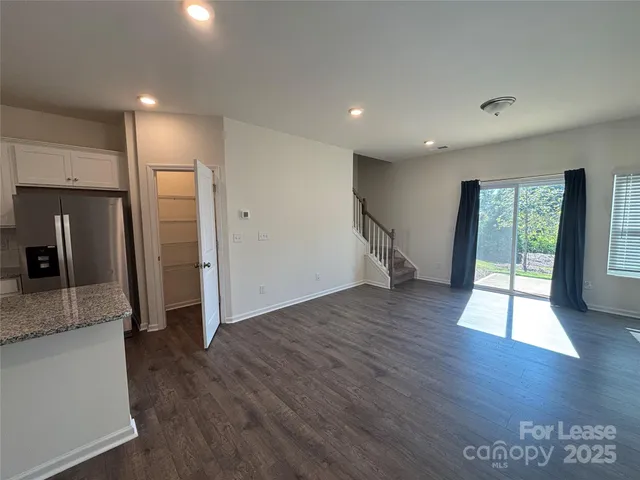 an empty room with wooden floor and a kitchen