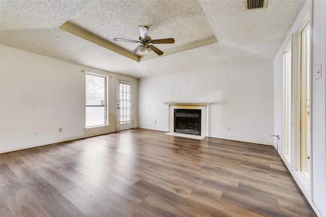 an empty room with wooden floor fan and windows