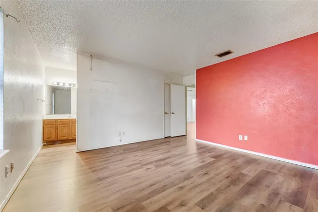 a view of an empty room with wooden floor and a bathroom