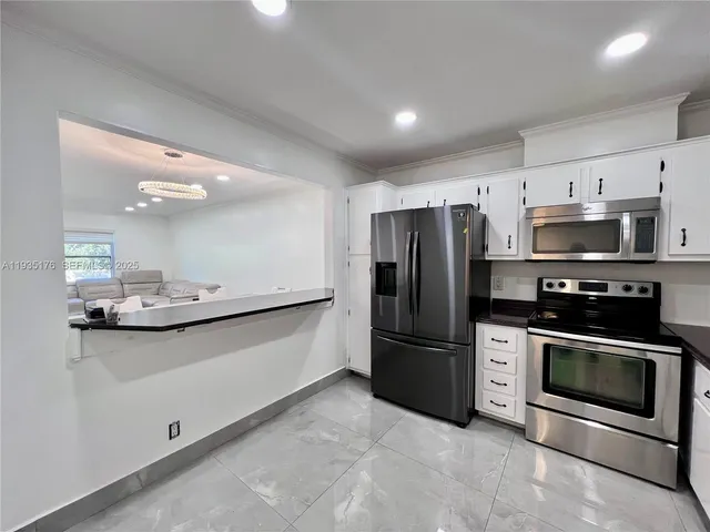 a kitchen with stainless steel appliances a sink a stove a microwave and a refrigerator