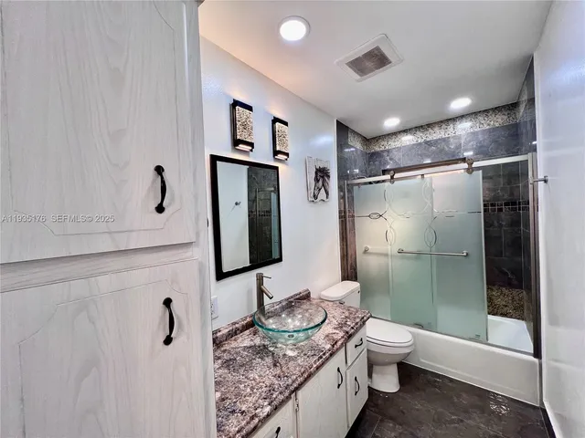 a bathroom with a granite countertop sink toilet and shower