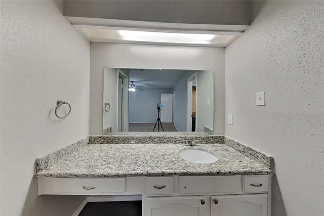 a bathroom with a granite countertop sink and a mirror
