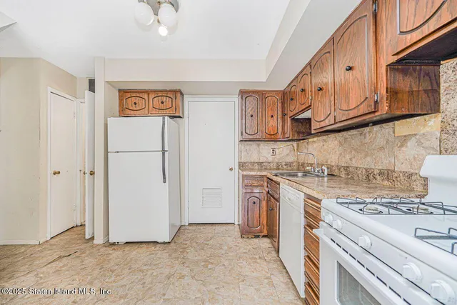 a view of an empty room with kitchen and a window