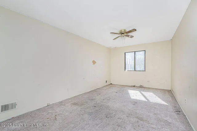 an empty room with windows and ceiling fan