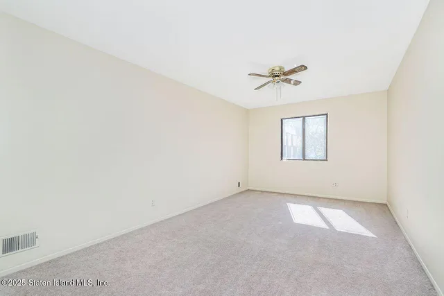 an empty room with windows and chandelier fan