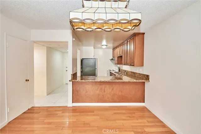 a view of a kitchen with kitchen island a sink wooden floor and a chandelier