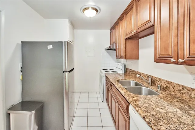 a kitchen with stainless steel appliances granite countertop a sink a refrigerator and a stove