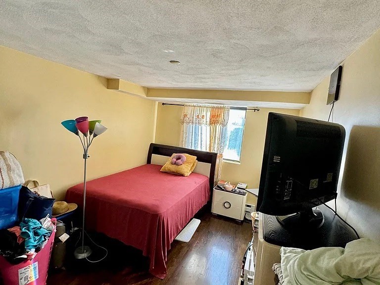 205 Ferry Street, Unit 101 Everett, MA 02149 - Photo 9 of 10 a bedroom with a bed and wooden floor