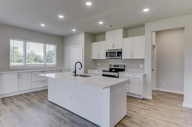 a kitchen with stainless steel appliances granite countertop a sink dishwasher a refrigerator and a stove with wooden floor