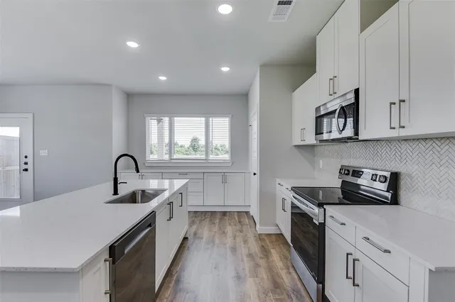 a kitchen with kitchen island a sink appliances cabinets and a counter top space
