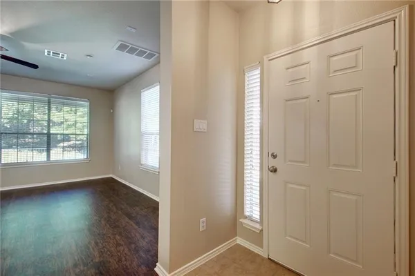 an empty room with wooden floor and windows with curtains