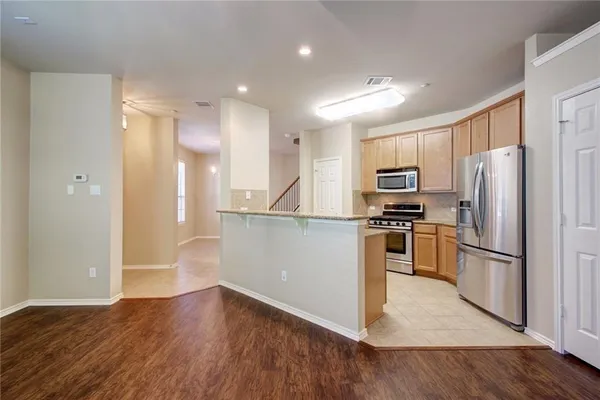 a view of kitchen with stainless steel appliances refrigerator stove microwave and cabinets