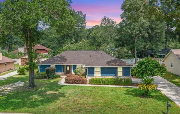 a front view of a house with a yard and green space